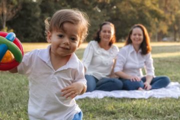 A joyful family enjoying a picnic in the park with a playful toddler in the foreground.